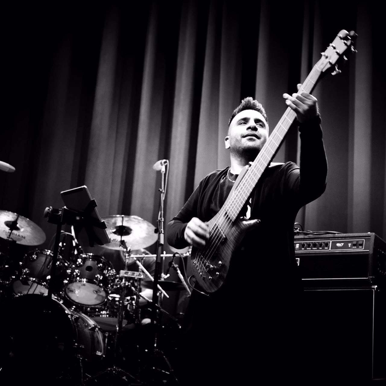 Ali Sanaei playing bass on stage in black and white